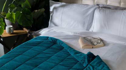 A bed with green velvet weighted blanket